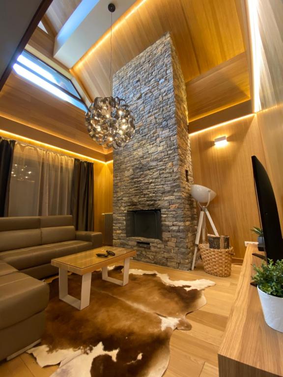 uma sala de estar com um sofá e uma lareira de pedra em Vila Tara em Žabljak