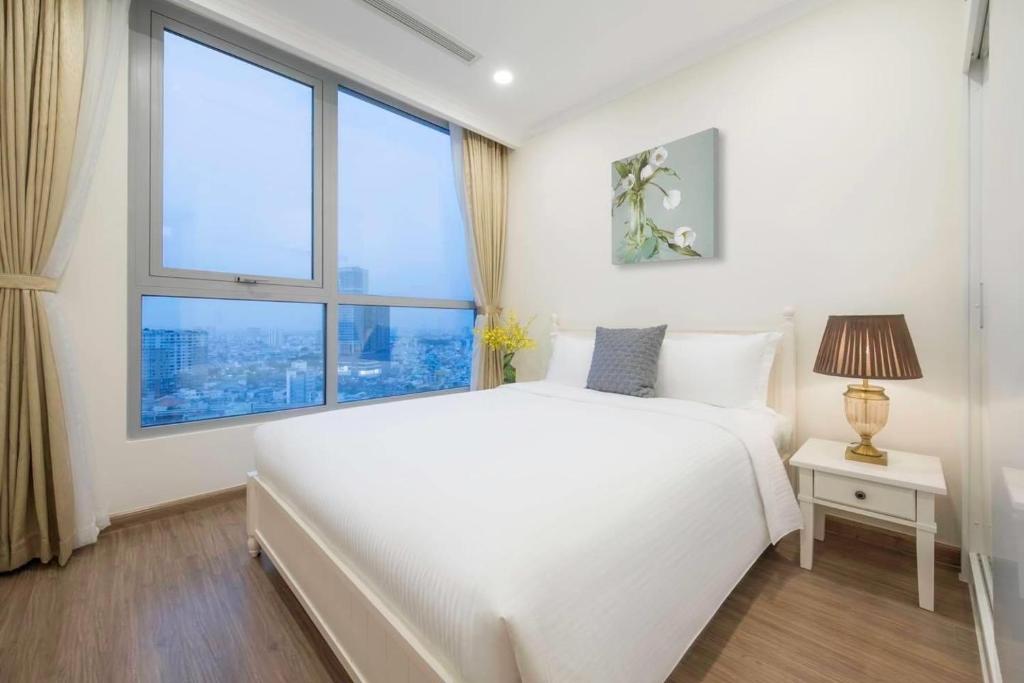 um quarto branco com uma cama grande e janelas grandes em Vinhomes Landmark 81 em Ho Chi Minh