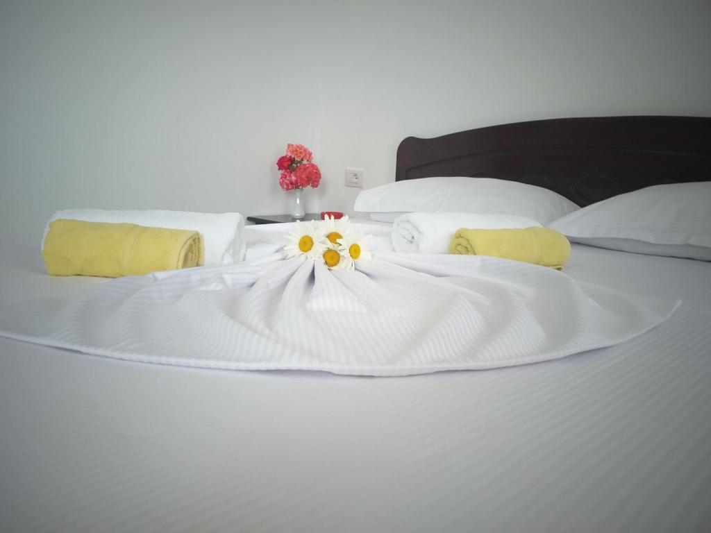 a white bed with flowers on top of it at Grand Seaview Apartments in Ksamil