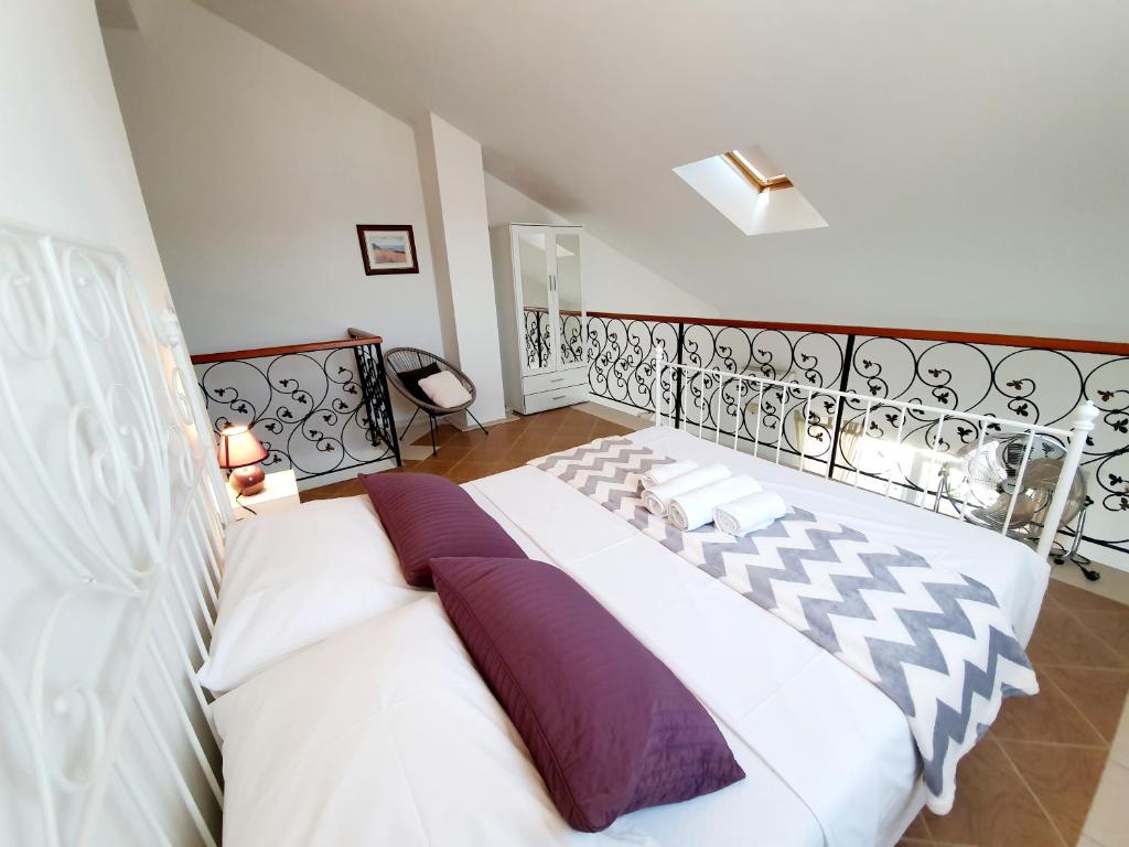 a bedroom with a large white bed with purple pillows at Apartmani Mikulić in Sevid