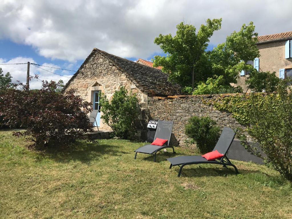 2 chaises assises devant une maison en pierre dans l'établissement Le gite du Larzac à Brunas, à Creissels