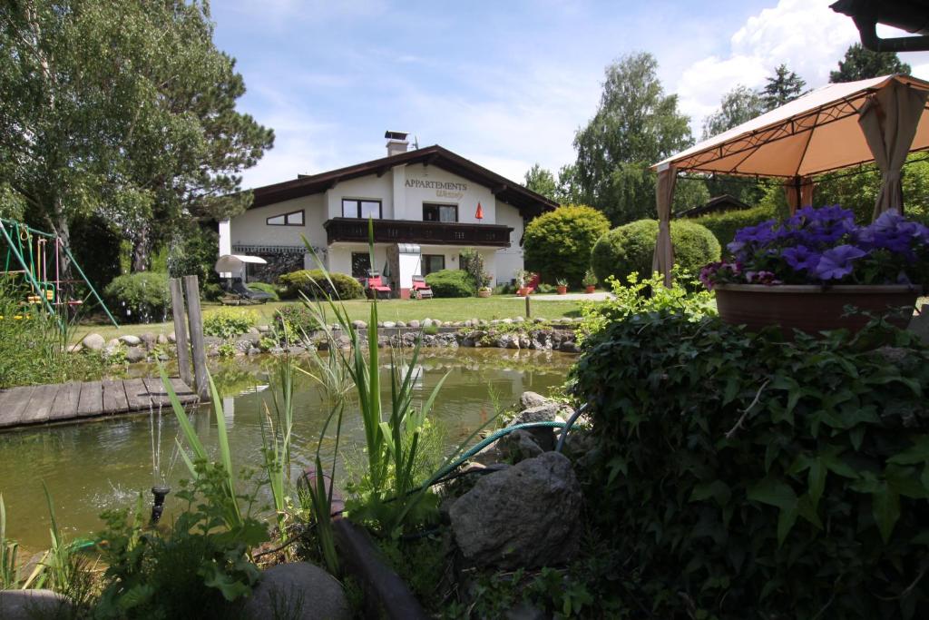 einen Garten mit einem Teich vor einem Haus in der Unterkunft Wessely Appartements am Golfplatz in Innsbruck