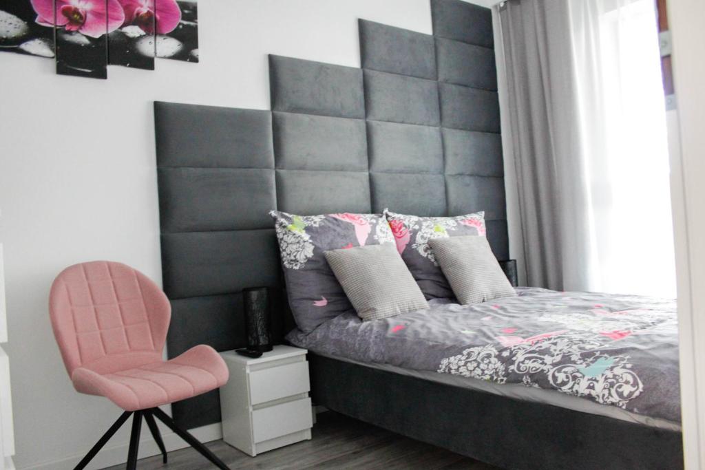 sypialnia z dużym zagłówkiem i różowym krzesłem w obiekcie Apartament Wrocław Centrum Galeria Magnolia we Wrocławiu