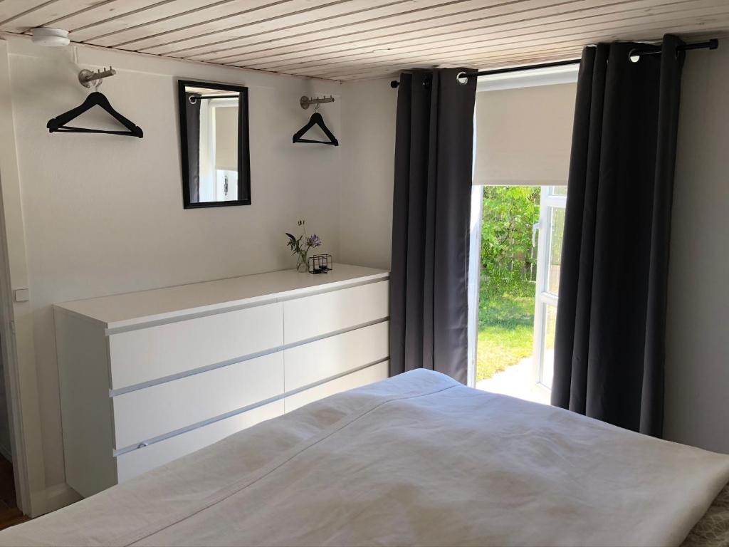 1 dormitorio con cama, espejo y ventana en Hyggelig ferielejlighed en Skagen