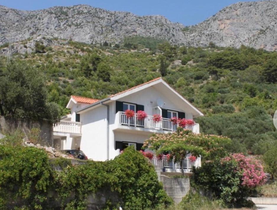 a white house with red flowers on balconies at Vila Druzijanic in Brist