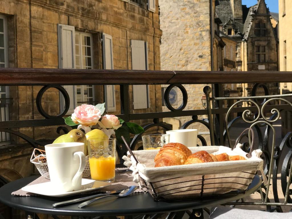 a table with a basket of pastries on a balcony at L appart d en face in Sarlat-la-Canéda
