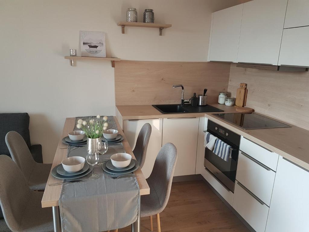 una cucina con tavolo e sedie e una cucina con armadietti bianchi di KaVi Apartments #1, TOP sunset view a Plzeň