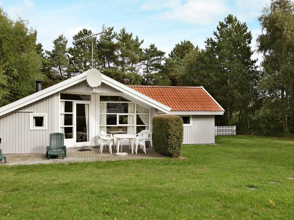 a white shed with a table and chairs in a yard at 8 person holiday home in R dby in Kramnitse