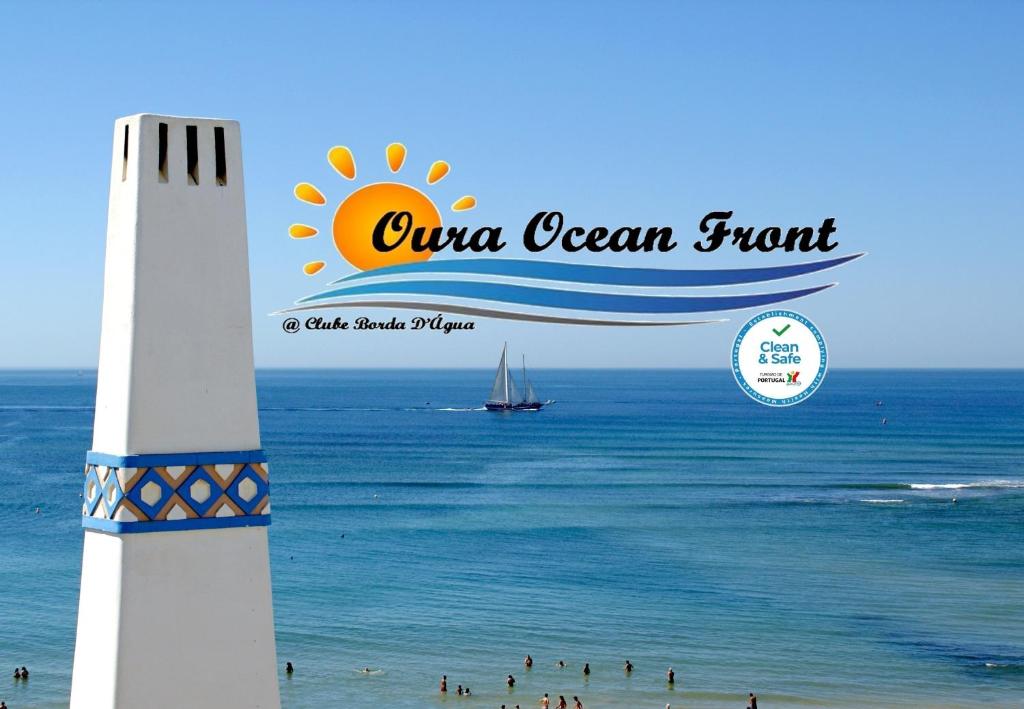 a lighthouse on a beach with people in the water at Oura Ocean Front in Albufeira