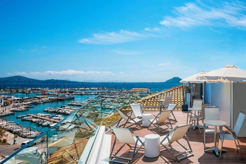 a balcony with chairs and a harbor with boats at Hotel Eolo in Port de Pollensa