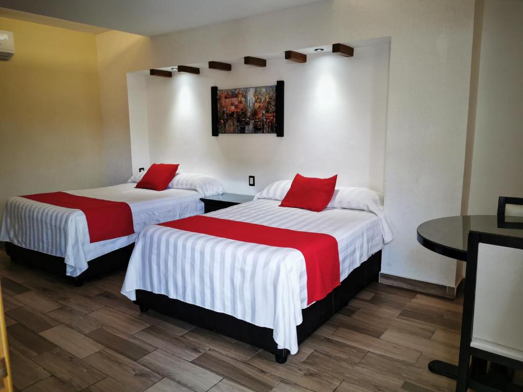 two beds with red pillows in a hotel room at Hotel Campestre Don Luis in Huajuapan de León