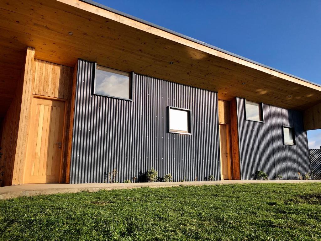 a modern house with a wooden facade with a grass at Line Hotel Patagonia in Puerto Natales
