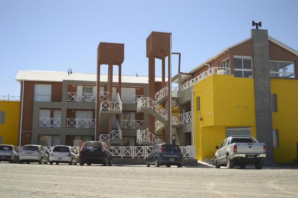 a parking lot with cars parked in front of buildings at Complejo Bahia Ballenas in Rawson