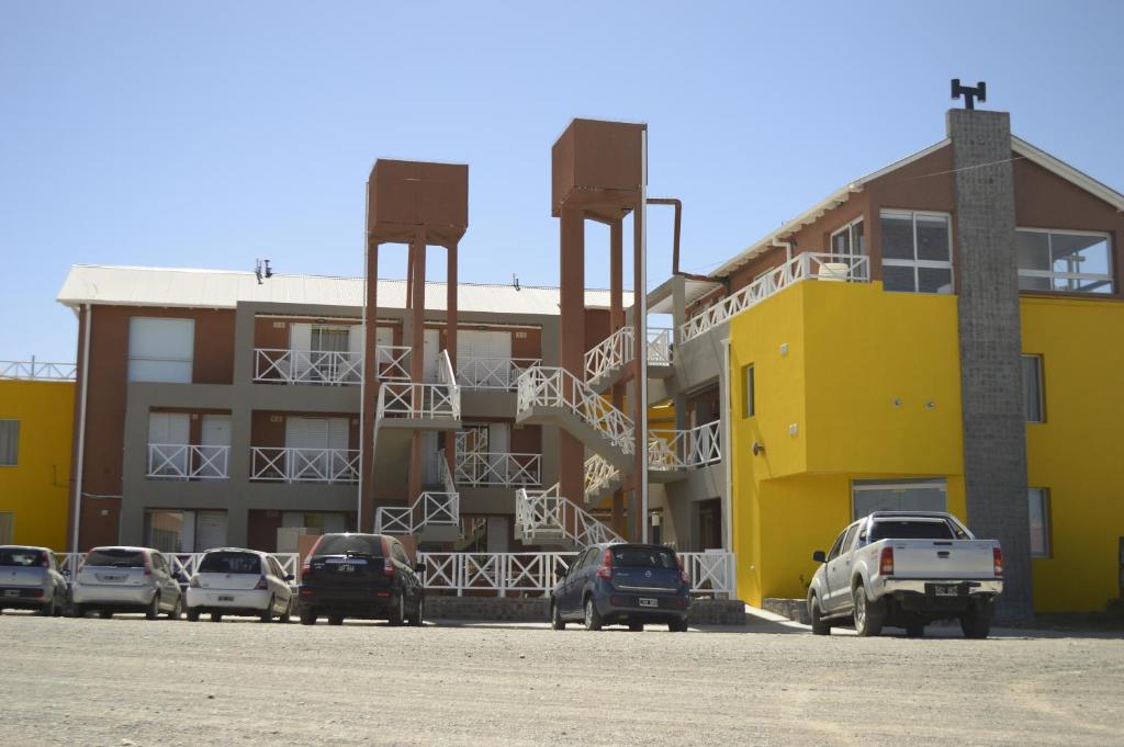 un aparcamiento con coches estacionados frente a los edificios en Complejo Bahia Ballenas en Rawson