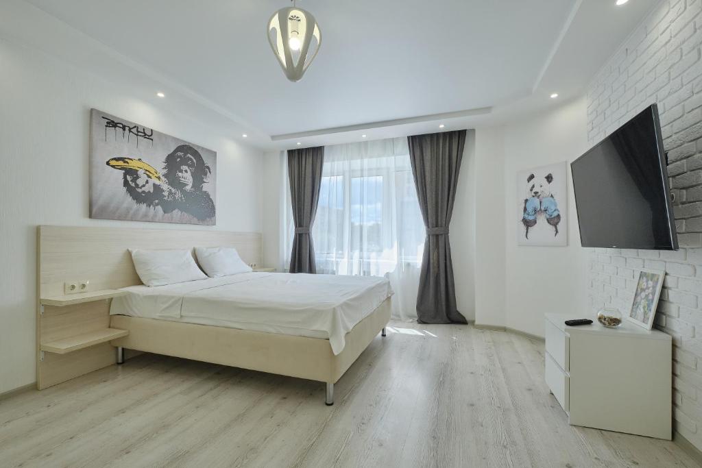 a white bedroom with a bed and a tv at Apartment Petrovskie on Frunze 46 in Tomsk