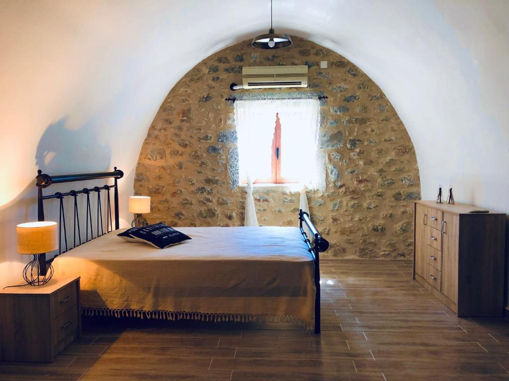 a bedroom with a bed in a stone wall at Kamares Stone House 1 in Álika