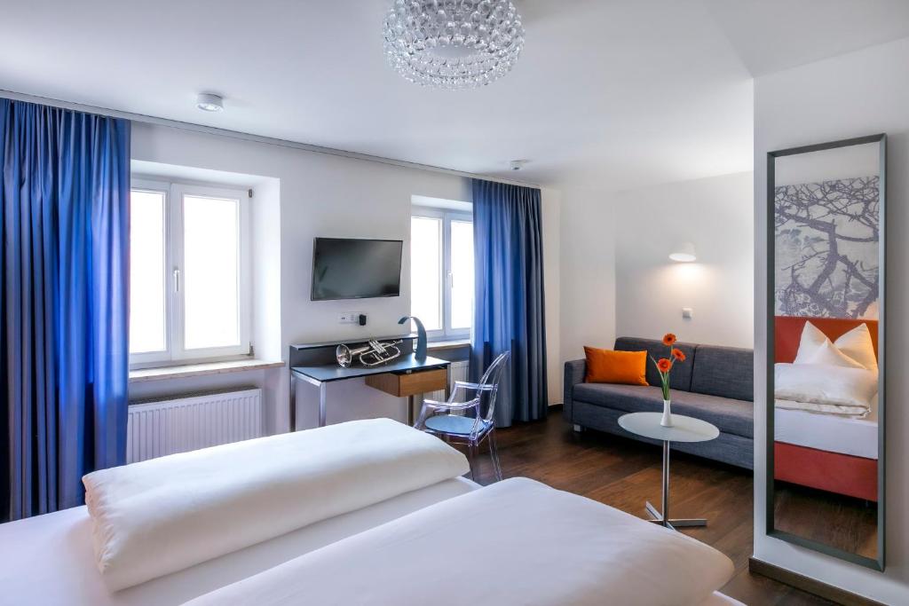 レーゲンスブルクにあるホテル ミュンヘナー ホフ ウント ブラウアー トゥルムのベッドとソファ付きのホテルルーム