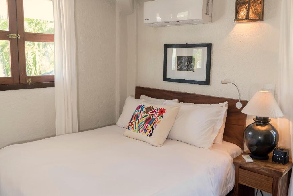 a bedroom with a bed with white sheets and a lamp at Villas Carrizalillo in Puerto Escondido