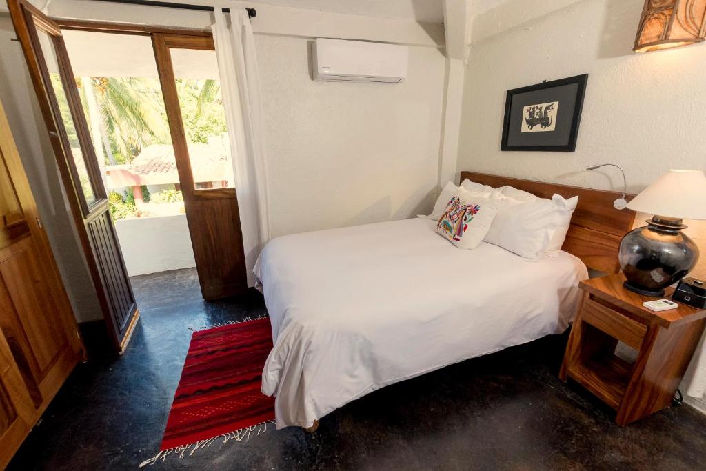 a bedroom with a white bed and a table with a lamp at Villas Carrizalillo in Puerto Escondido