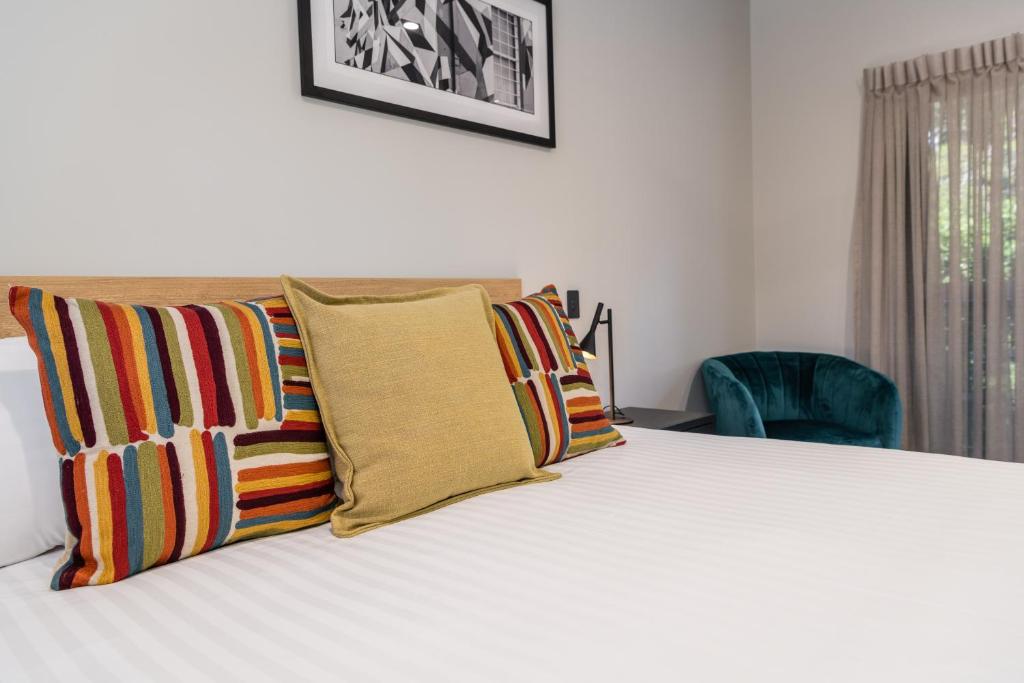 um quarto com uma cama com almofadas coloridas em AVENUE MOTEL APARTMENTS em Toowoomba