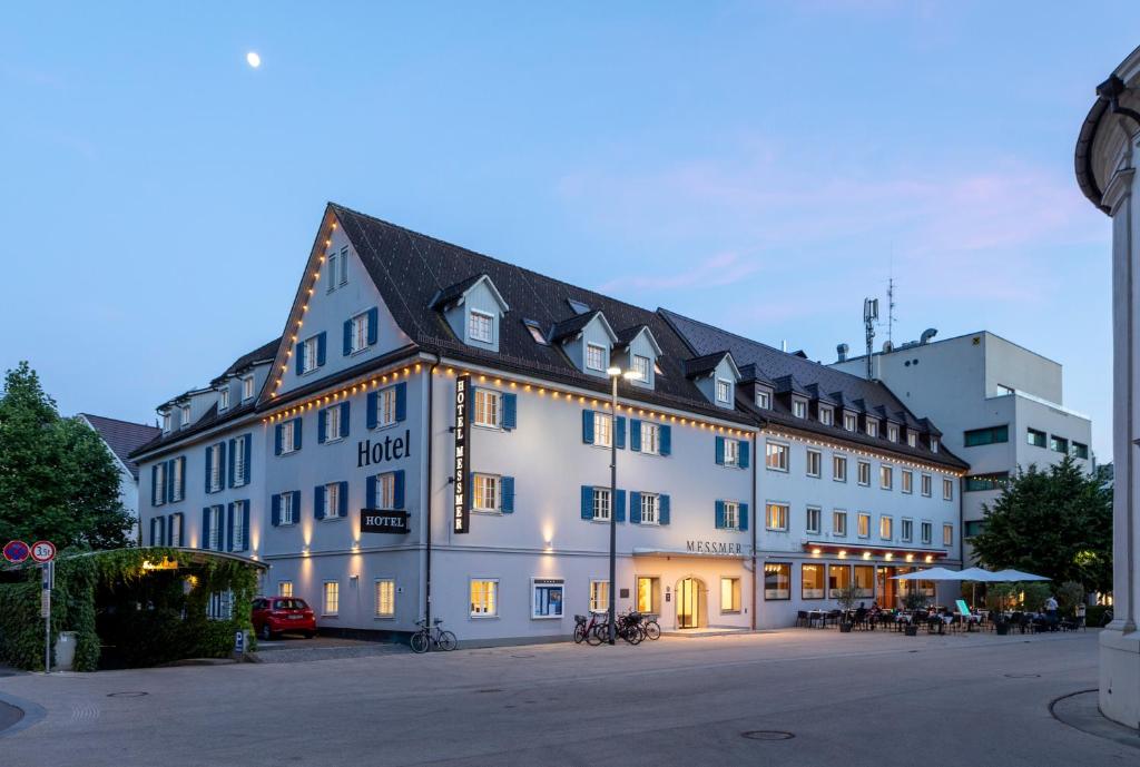 ein großes weißes Gebäude mit schwarzem Dach in der Unterkunft Hotel Messmer in Bregenz