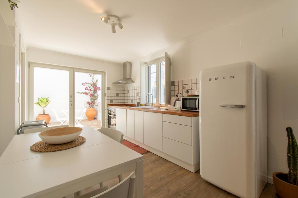 a kitchen with a white refrigerator and a table at Casa Carolina in Vila Real de Santo António