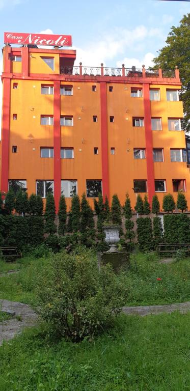 a large orange building with trees in front of it at Casa Nicoli in Băile Olăneşti