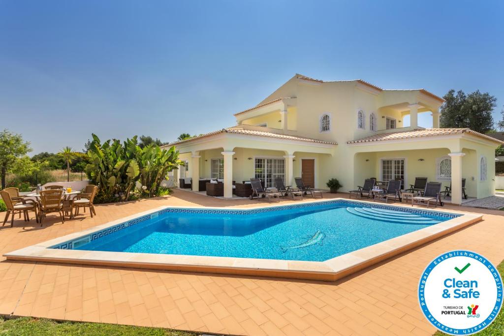 a villa with a swimming pool in front of a house at Villa Amarela in Alvor