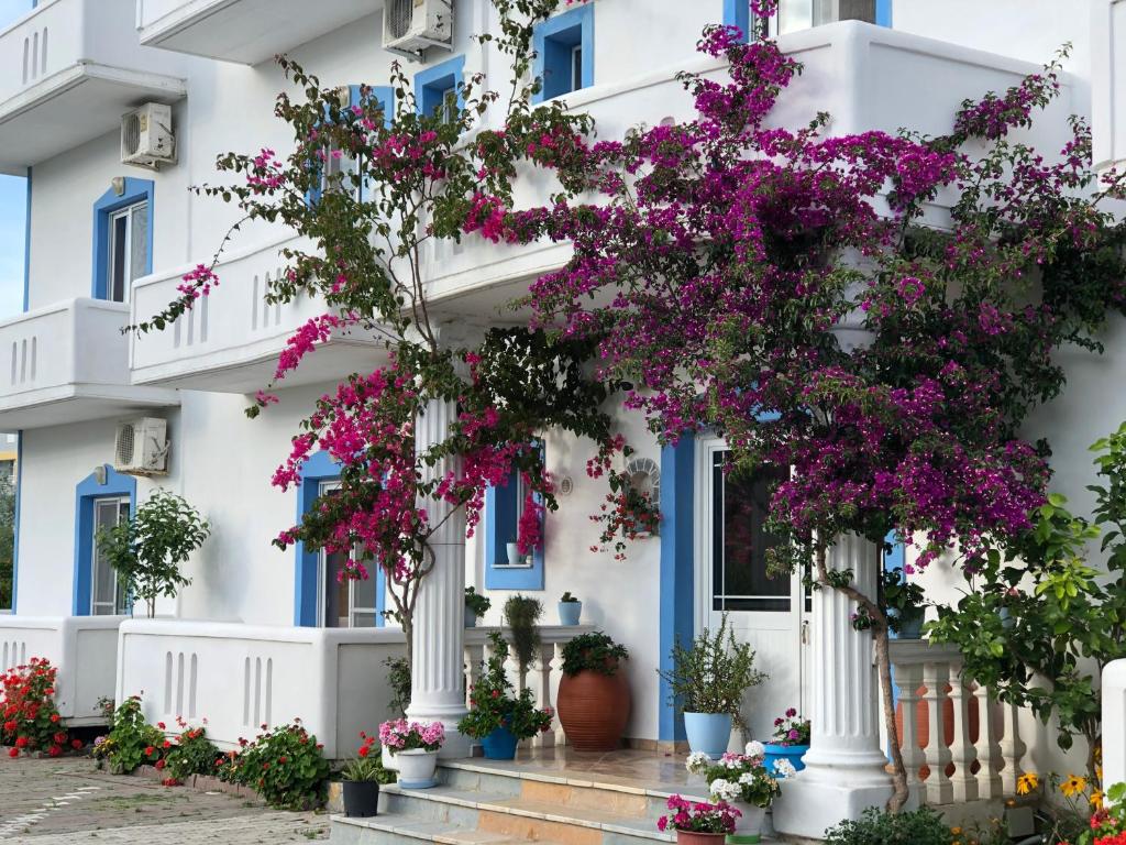 a white building with blue windows and purple flowers at Romantika in Shëngjin