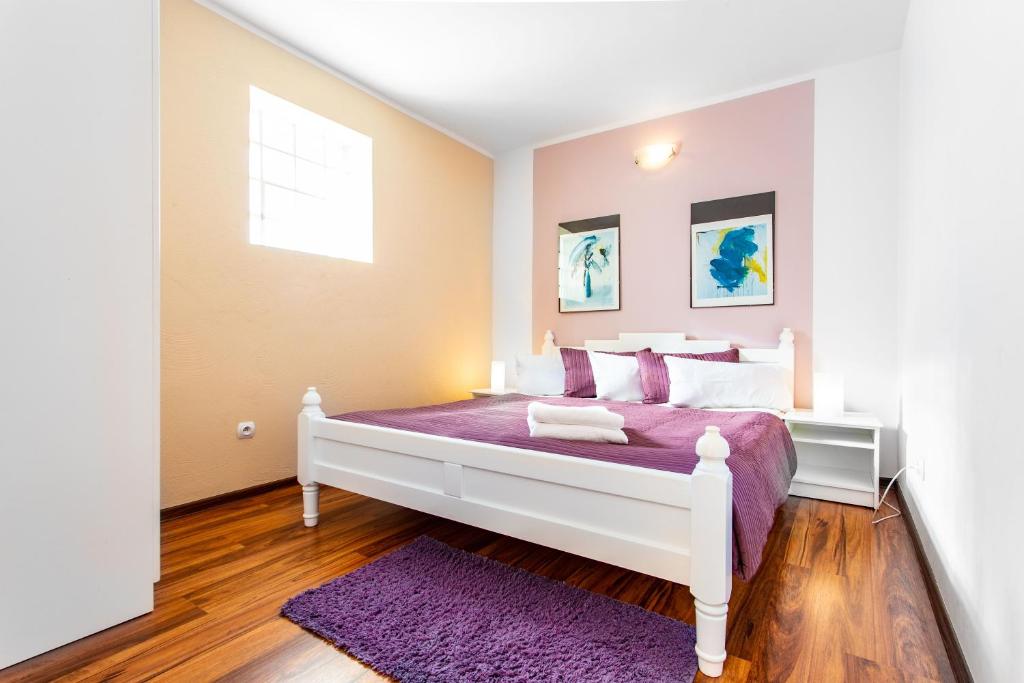 sypialnia z białym łóżkiem z fioletową pościelą i oknem w obiekcie Plaża Apartament w mieście Ustronie Morskie