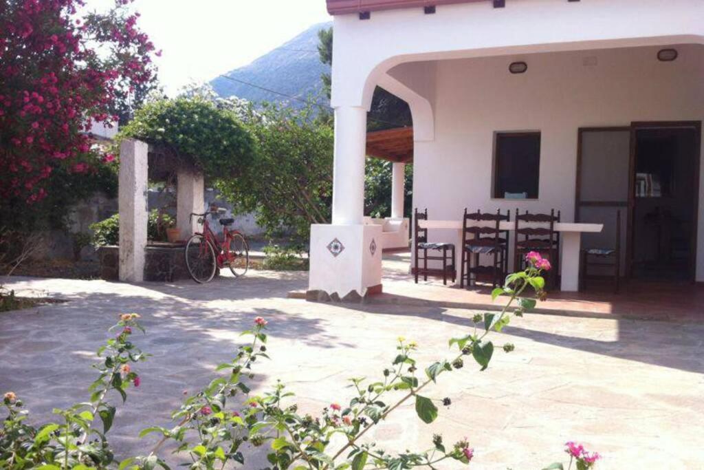 a house with a table and chairs in front of it at Villa by the Vulcano - 55 mq plus large garden and patio in Vulcano