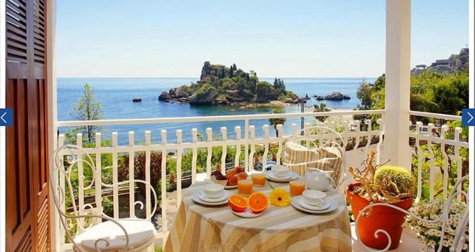 un tavolo su un balcone con vista sull'oceano di Orata & Spigola Apartments Taormina a Taormina