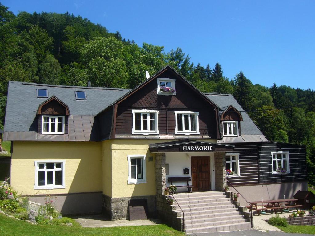 a yellow and black house with trees in the background at Chata Harmonie in Bedřichov