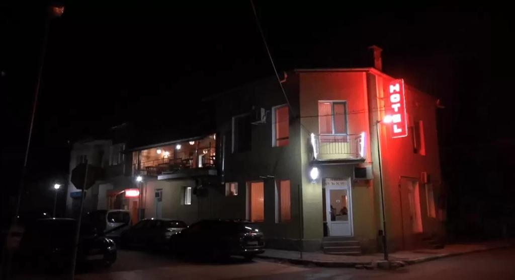un edificio rojo con un letrero de neón por la noche en Семеен хотел Лъки en Byala Slatina
