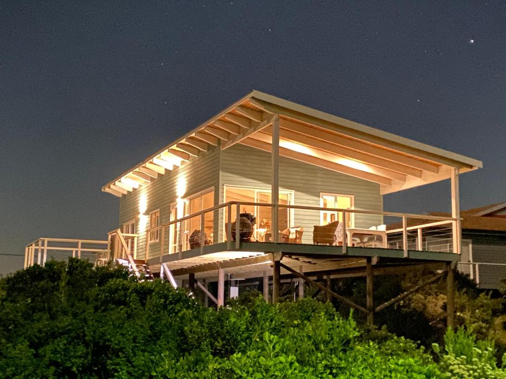 a house sitting on top of a bluff at night at The Blue Dragonfly in Jeffreys Bay