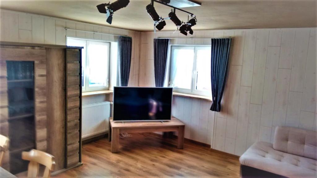 uma sala de estar com televisão numa mesa e duas janelas em Ferienwohnung Schaule em Bolsterlang
