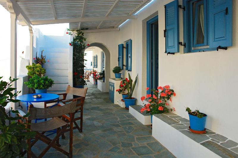 a patio with a table and chairs and flowers at Artemis Rooms in Chora Folegandros