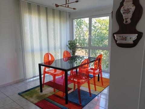 une salle à manger avec une table noire et des chaises rouges dans l'établissement Appartement FOCH à COLMAR, à Colmar