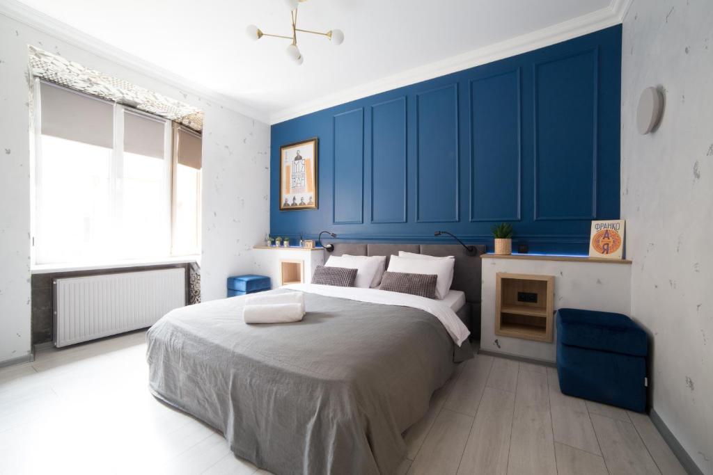 1 dormitorio con 1 cama grande y paredes azules en Дизайнерські апартаменти на вулиці Краківській 17 в центрі Львова, en Leópolis