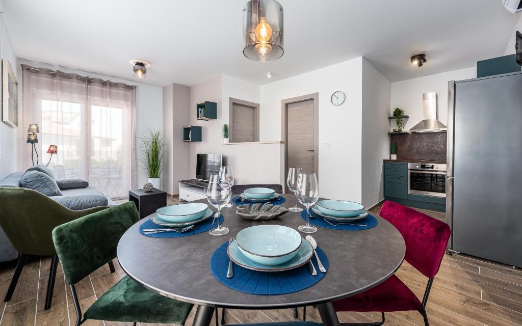 una sala da pranzo con tavolo, piatti e bicchieri da vino di Apartment Sabbia a Medulin