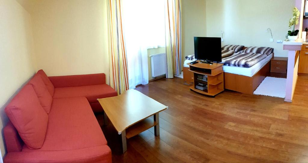 een woonkamer met een rode bank en een tv bij Apartment 202 in Tatranská Lomnica