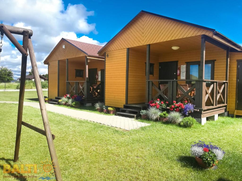 a house with a garden and a swing at Balti Domki Letniskowe in Dębina