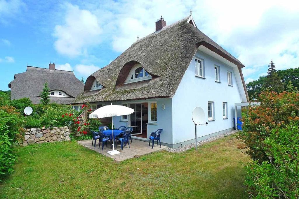 a white house with a table and chairs and an umbrella at Ferienhaus das Blaue Haus WS-9a in Born