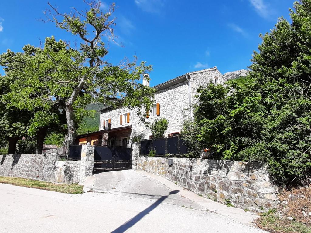 a house with a stone wall and a tree at Villa Kozljak, for 10 people, pool in Kozljak