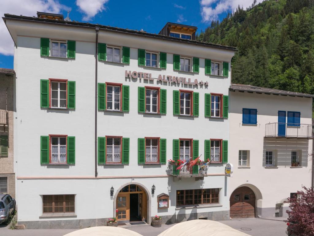 ein großes weißes Gebäude mit grünen Rollläden in der Unterkunft Altavilla, Rooms & Breakfast in Poschiavo