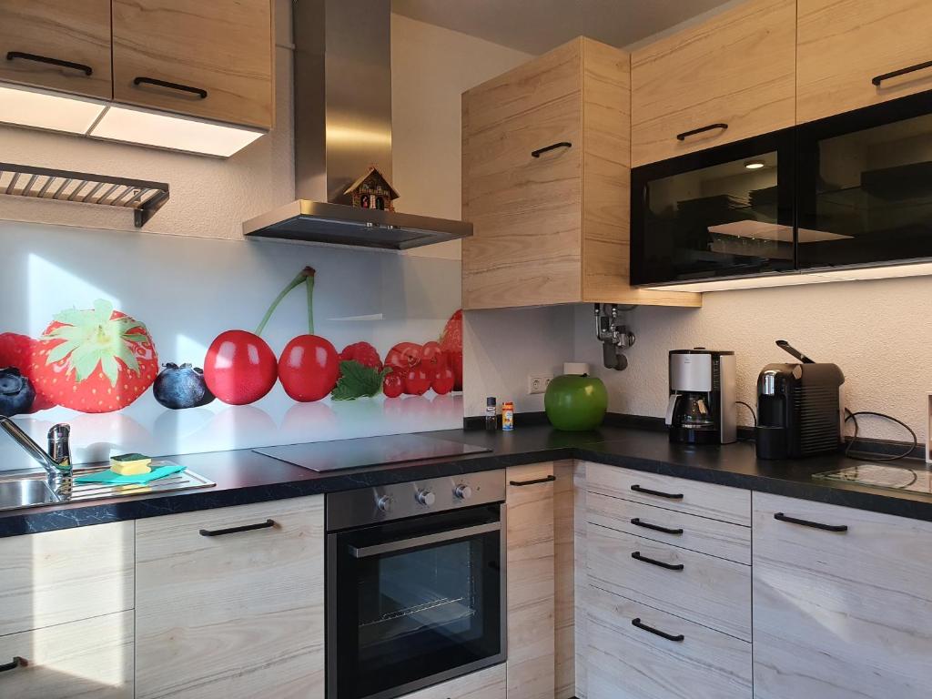 una cocina con armarios de madera y tomates en la pared en Fewo Schwarzwaldfreude en Freudenstadt