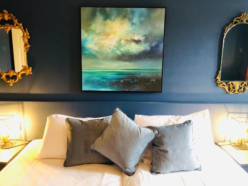 a bedroom with a bed with pillows and a painting on the wall at The Waterside Apartment 112 Harbour Mills in Westport