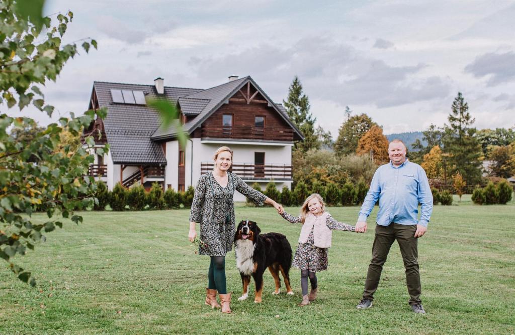 a family with their dog in front of a house at Malowane Wierchy in Gładyszów