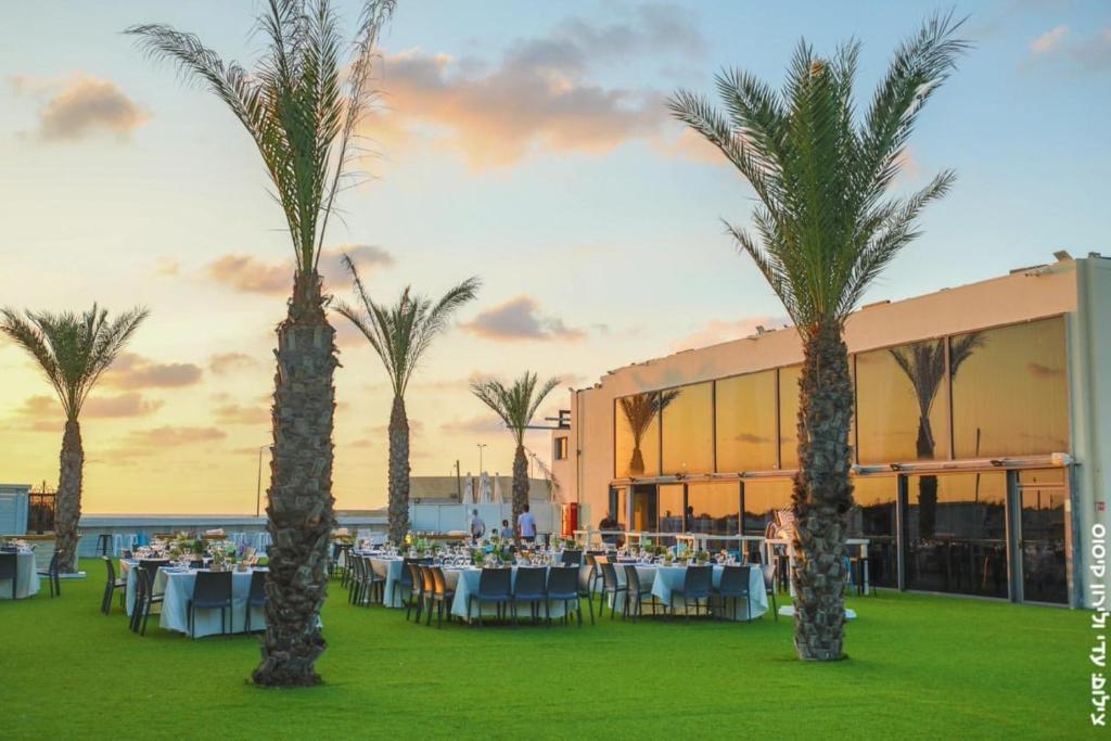 a group of palm trees in front of a building at El Yam in Netanya