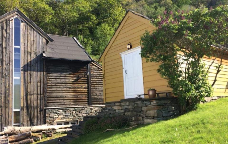 a yellow house with a white door and a stone wall at Hardanger Kulturgalleri in Herand